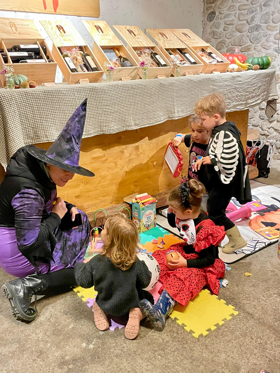 Sorcière jouant avec les enfants dans un coin jeux d’un domaine viticole.